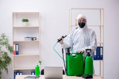Young male contractor disinfecting office during pandemic