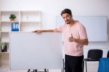 Genç erkek öğretmen salgın sırasında sınıfta.