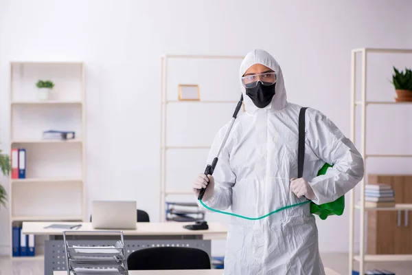 Jovem empreiteiro masculino desinfetando escritório durante pandemia — Fotografia de Stock