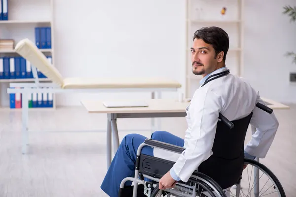 Jonge mannelijke arts in rolstoel werkzaam in de kliniek — Stockfoto
