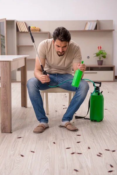 Young man exterminating cockroaches at home — Stock Photo, Image