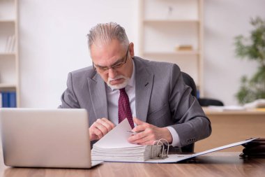 Ofiste çalışan yaşlı bir erkek.