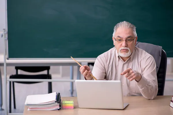 Velho professor na frente de quadro negro em conceito telestudy — Fotografia de Stock