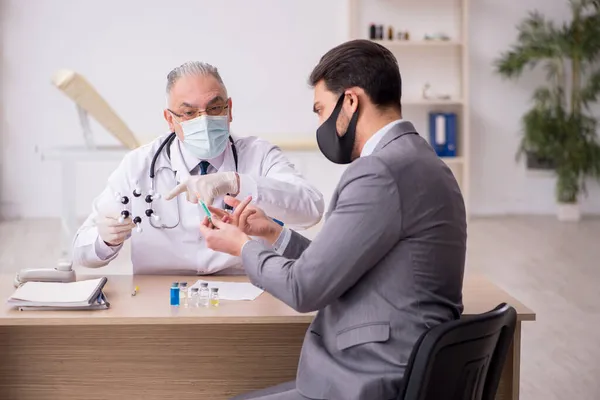 젊은 사업가가 예방 접종을 위해 연로 한 남성 의사를 방문하다 — 스톡 사진