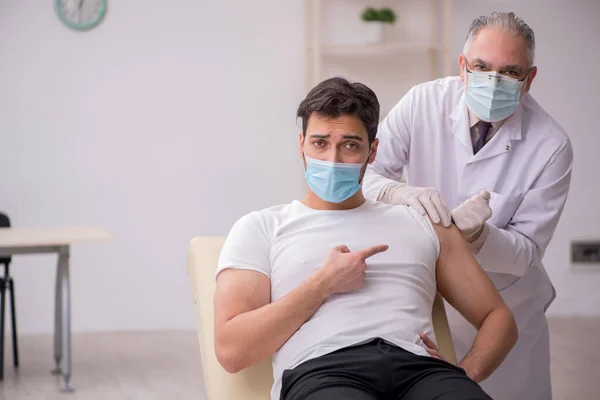 Junge männliche Patientin besucht alten Arzt im Impfpass — Stockfoto