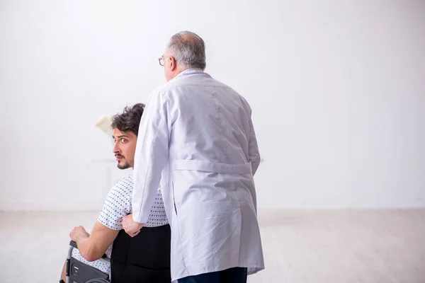 Старый врач-психиатр осматривает молодого пациента с ограниченными возможностями — стоковое фото