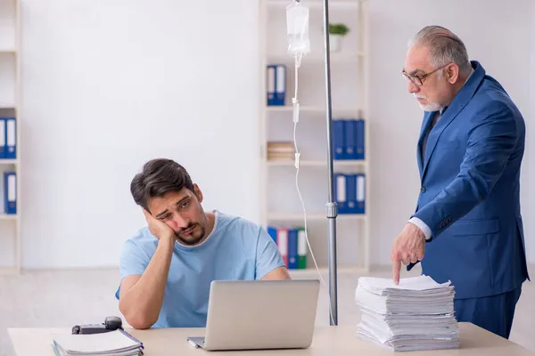 Jonge mannelijke werknemer voelt zich slecht op de werkplek — Stockfoto