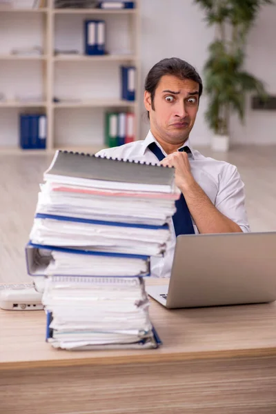 Jeune employé masculin et beaucoup de travail au bureau — Photo