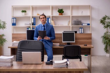 Genç bir erkek çalışan ve ofiste bir sürü iş var.