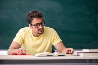 Tahtanın önünde genç bir erkek öğrenci.