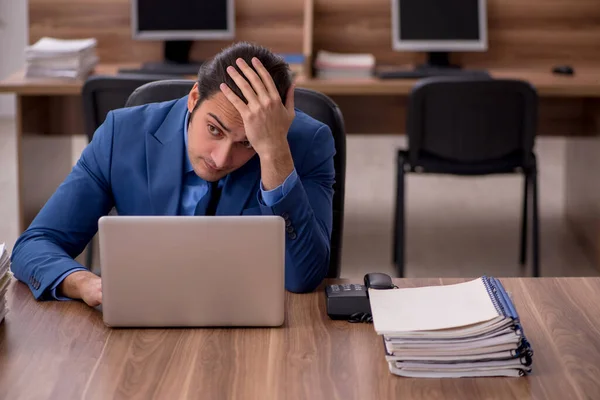 Jonge mannelijke werknemer en veel werk op kantoor — Stockfoto