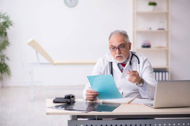 Klinikte çalışan yaşlı erkek doktor.