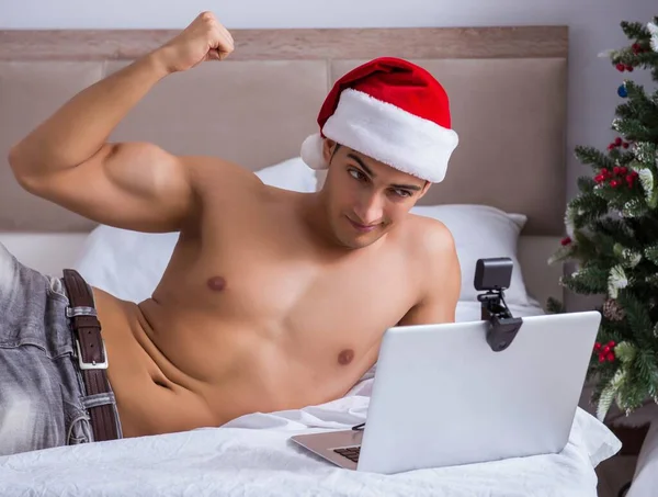 Sexig man i sängen bär tomte hatt i jul koncept — Stockfoto