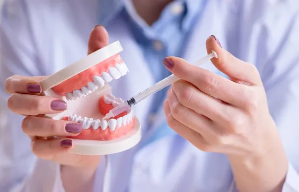 Mujer dentista practicando trabajo en modelo de diente — Foto de Stock