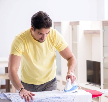 Yakışıklı koca evde kıyafet ütülüyor.