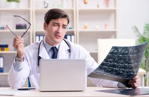 Ung läkare tittar på röntgenbilder på kliniken — Stockfoto