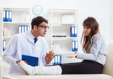 Kırık bacaklı bir hastayı muayene eden doktor.