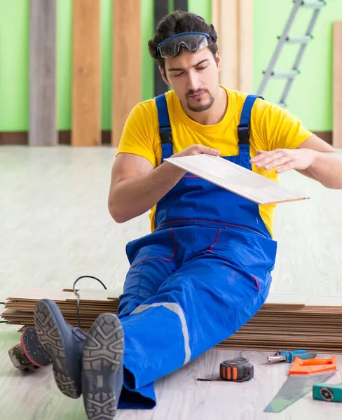 Empreiteiro profissional que coloca piso em casa — Fotografia de Stock
