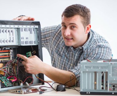 Genç teknisyen atölyede bilgisayar tamir ediyor.