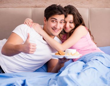 Mutlu bir aile yatakta kahvaltı yapıyor.
