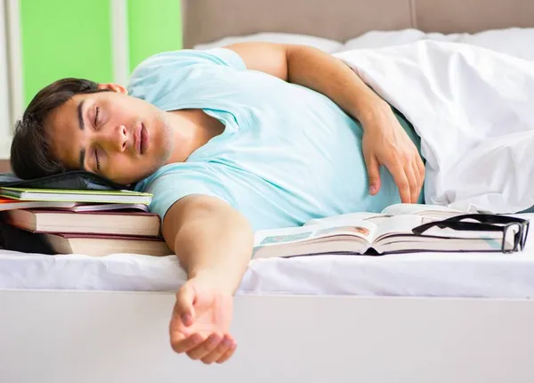 Estudante se preparando para exames em casa no quarto deitado na cama — Fotografia de Stock