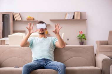 Evde sanal gözlük takan genç bir öğrenci.