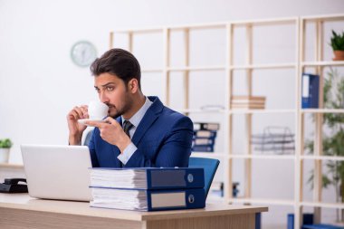 Genç ve yakışıklı bir çalışan teneffüste kahve içiyor.