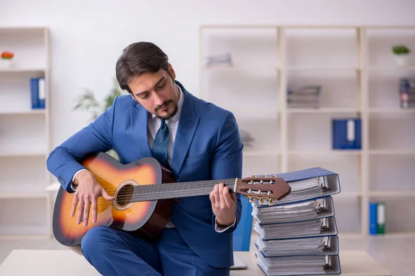 Joven empleado masculino tocando guitarra en el lugar de trabajo — Foto de Stock