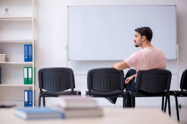 Genç erkek öğretmen salgın sırasında sınıfta.