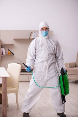 Young male contractor disinfecting at home