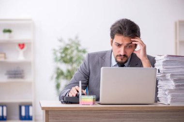 Genç bir erkek çalışan ve ofiste çok fazla iş var.