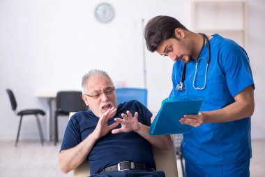 Yaşlı adam genç erkek doktoru ziyaret ediyor.