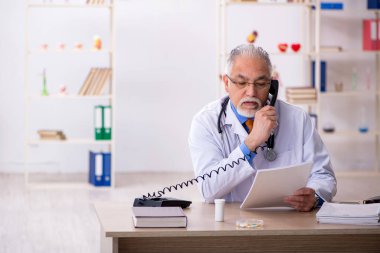 Klinikte çalışan yaşlı erkek doktor.