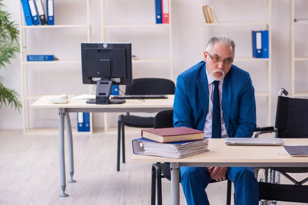 Alte männliche Angestellte im Rollstuhl sitzt im Büro — Stockfoto