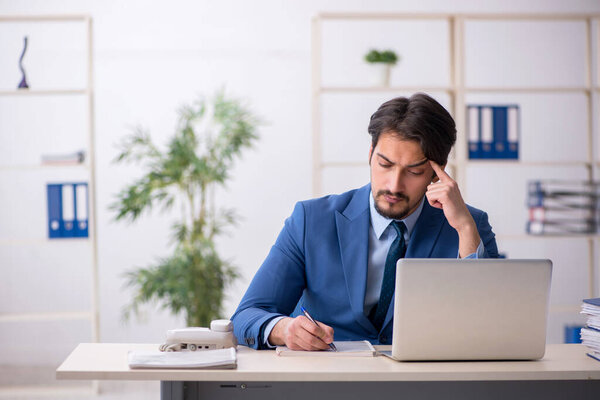 Young male employee and too much work in the office