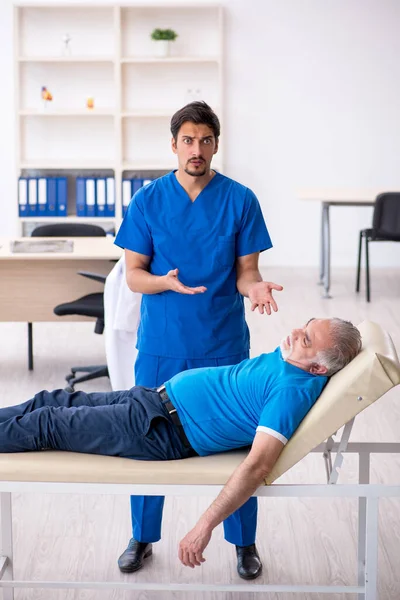 Old male patient visiting young male doctor — Stock Photo, Image