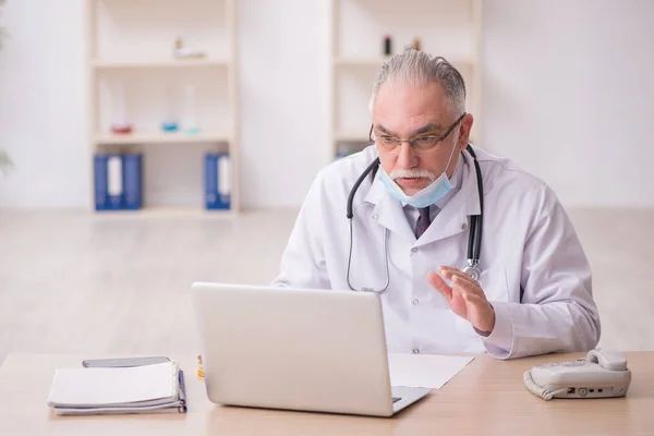 Старий чоловік лікар працює в клініці під час пандемії — стокове фото