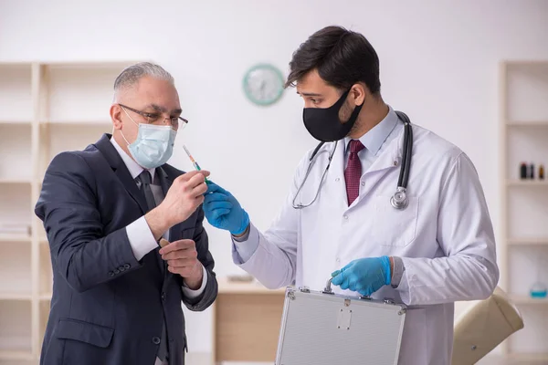 늙은 사업가가 예방 접종 허가서젊은 남성 의사를 방문하는 모습 — 스톡 사진