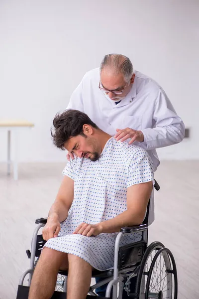 Old male doctor psychiatrist examining young disabled patient