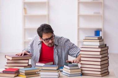 Genç bir erkek öğrenci ve sınıfta çok fazla kitap var.