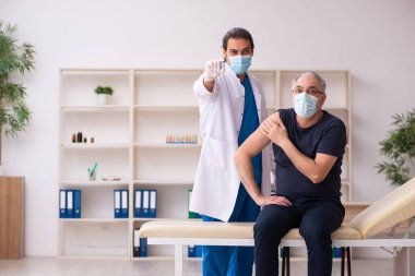 Yaşlı adam covid-19 aşı konseptinde genç doktoru ziyaret ediyor.