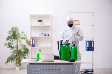 Young male contractor disinfecting office during pandemic