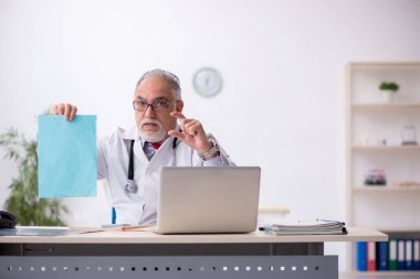 Klinikte çalışan yaşlı erkek doktor.