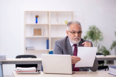 Ofiste çalışan yaşlı bir erkek.