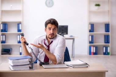 Ofisteki aşırı işten memnun olmayan genç bir erkek işçi.