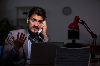 Genç erkek çalışan ofiste geç saatlere kadar çalışıyor.