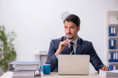 Genç erkek çalışan işyerinde oturuyor.