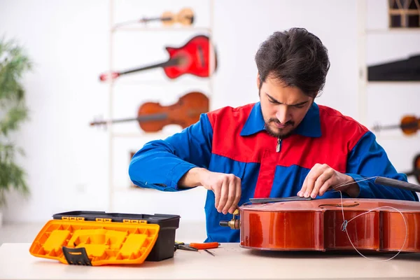Jeune réparateur masculin réparant des instruments de musique sur le lieu de travail — Photo