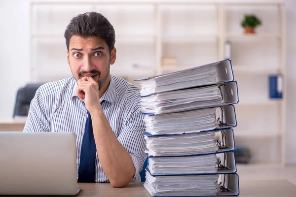 Ung manlig anställd och för mycket arbete på kontoret — Stockfoto