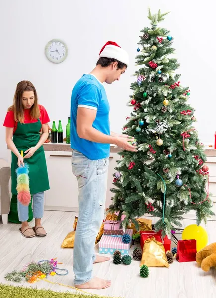 Молодая семья убирает квартиру после рождественской вечеринки — стоковое фото